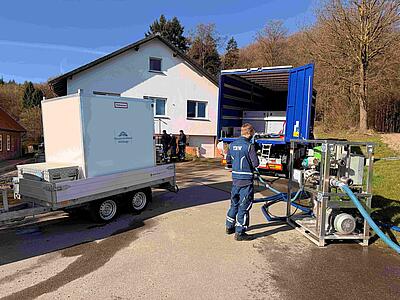 Kleiner Tank des Wasserverbandes auf Anhänger und großer Tankwagen des THW mit Schlauch und Mitarbeiter (mobile Wasserversorgung)