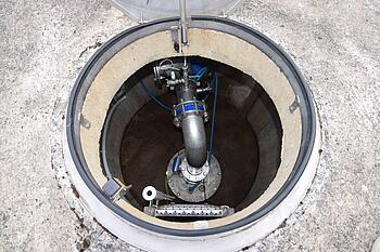 Blick ins Innere eines Brunnens: Armaturen und Rohre.
