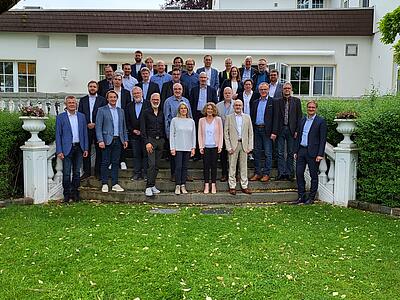 Gruppenbild mit 31 Konferenzteilnehmern höhengestaffelt auf der Treppe der Terrasse an Högers Hotel.
