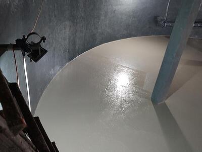 Blick in den Speicher: Der frische Beton der Bodenplatte ist sichtbar. Links steht eine Leiter.