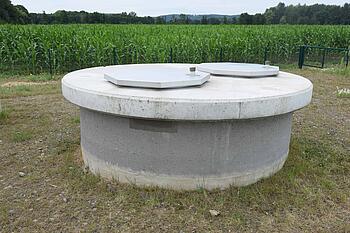 Ein großer Betonring mit Deckel in der Wiese - so unscheinbar ist ein Brunnen.