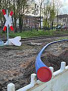Ein blaues PE-Rohr wird verlegt. Im Hintergrund die Eisenbahnlinie bei Bohmte.